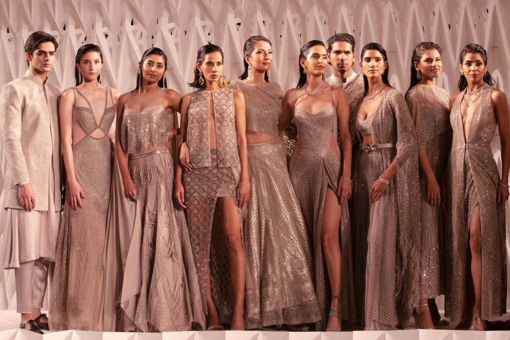 A group of stylish models in elegant attire posing indoors, showcasing contemporary fashion.